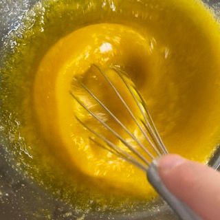 Una persona sta sbattendo un liquido giallo in una ciotola