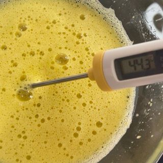 Un termometro digitale sta misurando la temperatura di un liquido giallo