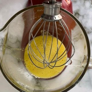 Un misurino di vetro riempito con liquido giallo e una frusta