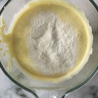 Una ciotola di vetro piena di un liquido giallo e zucchero a velo.