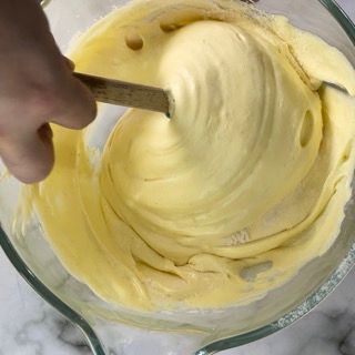 Una persona sta mescolando un liquido giallo in una ciotola con un cucchiaio.