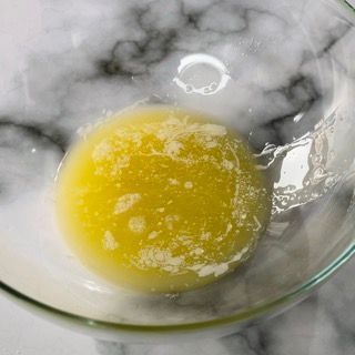 Primo piano di un liquido giallo in una ciotola di vetro su un tavolo.