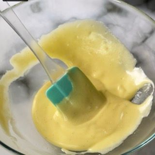 Una ciotola di liquido giallo con una spatola dentro