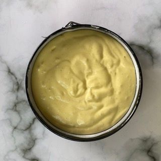 Una ciotola di salsa gialla su una superficie di marmo