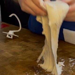 Una persona sta stendendo un pezzo di pasta su un tagliere