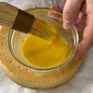 Una persona tiene un pennello sopra una ciotola di liquido giallo