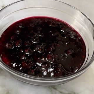 Una ciotola di vetro piena di salsa di frutti di bosco su un tavolo