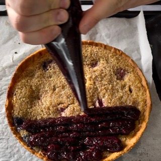 Una persona sta versando la salsa di ciliegie in una torta