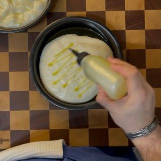 Una persona sta versando dell'olio in una ciotola di cibo