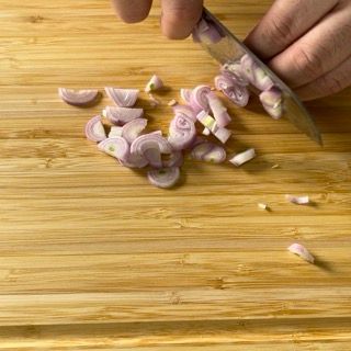 Una persona sta tagliando le cipolle su un tagliere di legno.
