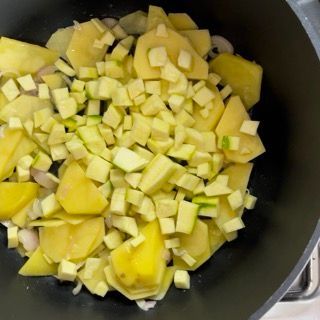 Una padella piena di patate tritate e cubetti