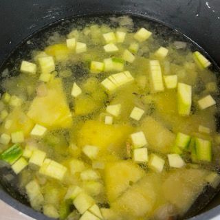 Una pentola di zuppa con dentro cubetti di verdure