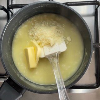 Una pentola di zuppa con burro e formaggio e una spatola dentro.