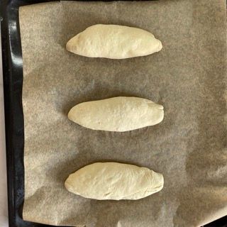 Tre pagnotte di pasta sono appoggiate su un pezzo di carta oleata