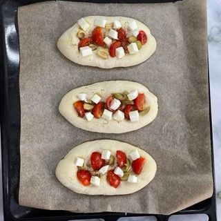 Tre pizze con pomodori, olive e formaggio su una teglia
