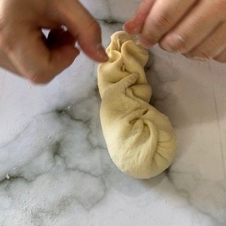 Una persona tiene in mano un pezzo di pasta su un tavolo.