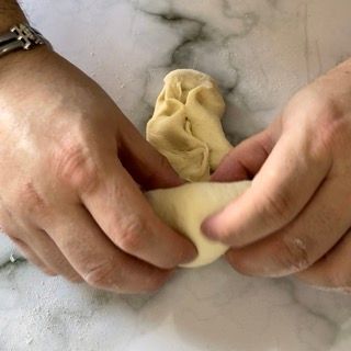 Una persona tiene in mano un pezzo di pasta.