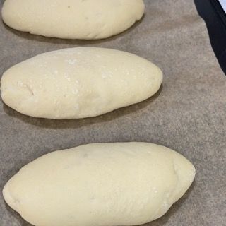 Tre rotoli di pasta sono appoggiati su un pezzo di carta oleata.