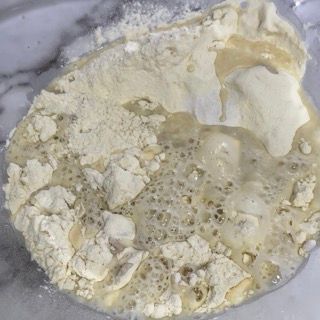 Primo piano di una ciotola di farina e liquido su un tavolo.