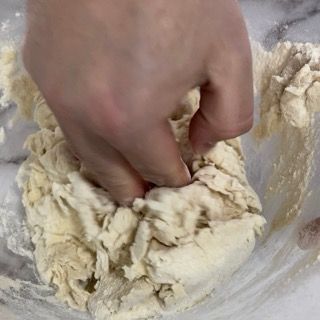 Una persona sta impastando l'impasto in una ciotola di vetro.