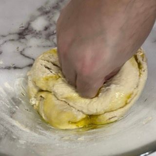 Una persona sta impastando l'impasto in una ciotola di vetro.