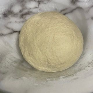 Una palla di pasta è appoggiata su una ciotola bianca.