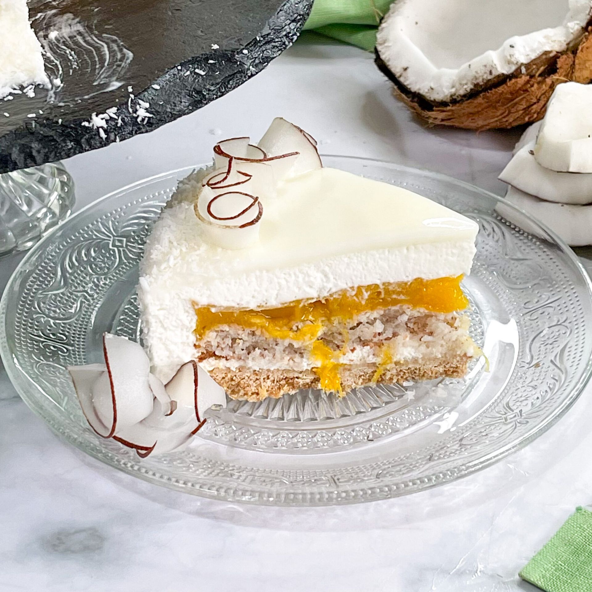 Una fetta di torta al cocco è su un piatto di vetro.