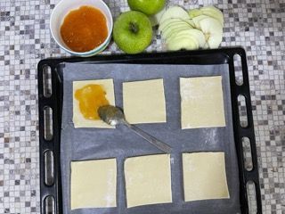 Un vassoio di pasta sfoglia con mele e marmellata sopra