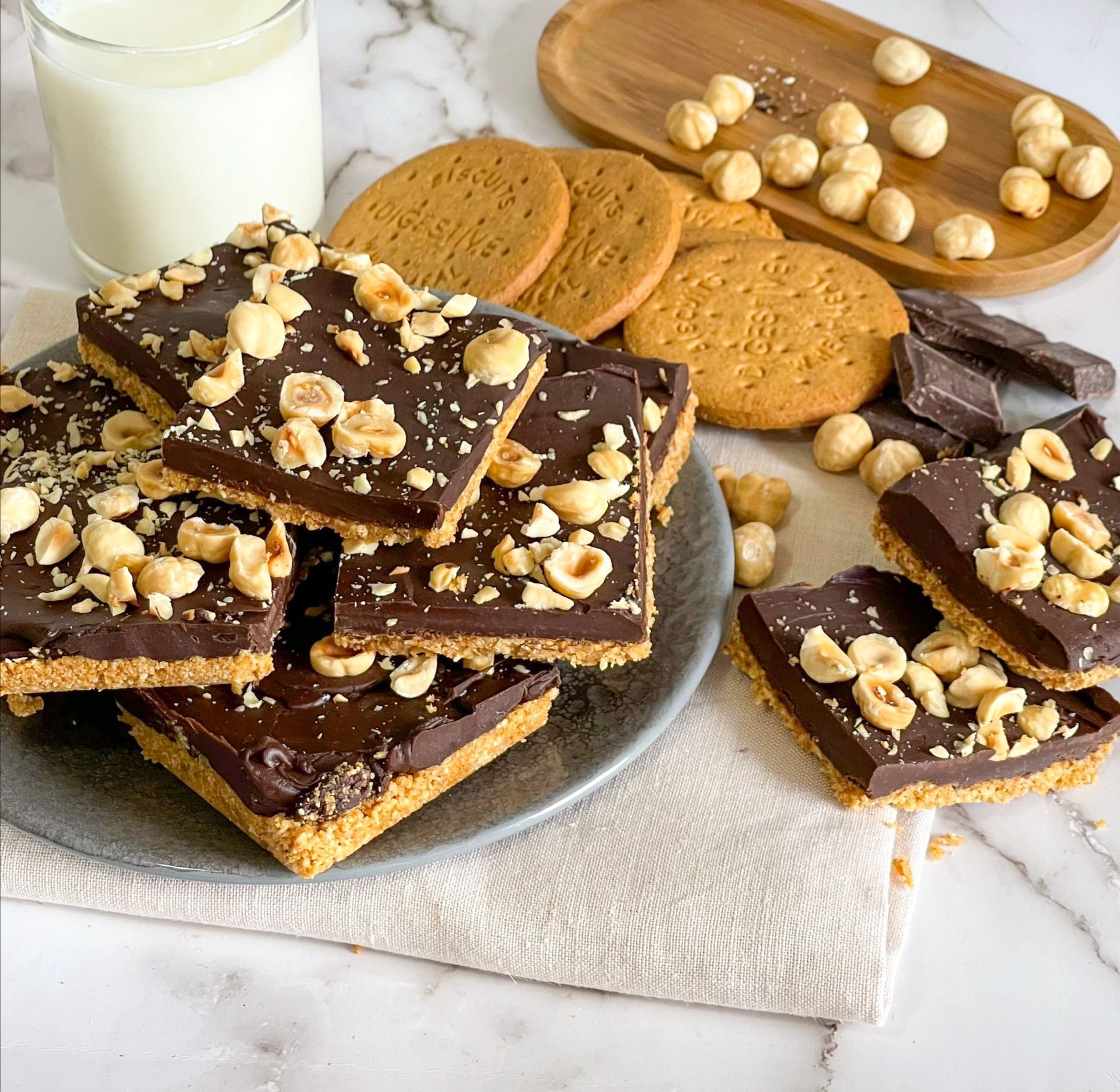 Un piatto di biscotti ricoperti di cioccolato con noci e un bicchiere di latte