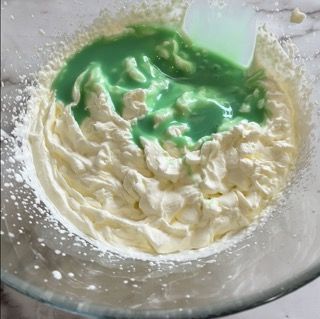 Una ciotola di panna montata con liquido verde e una spatola
