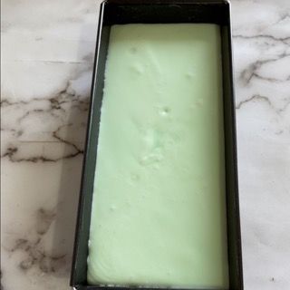 Una scatola nera piena di liquido verde è appoggiata su un bancone di marmo.