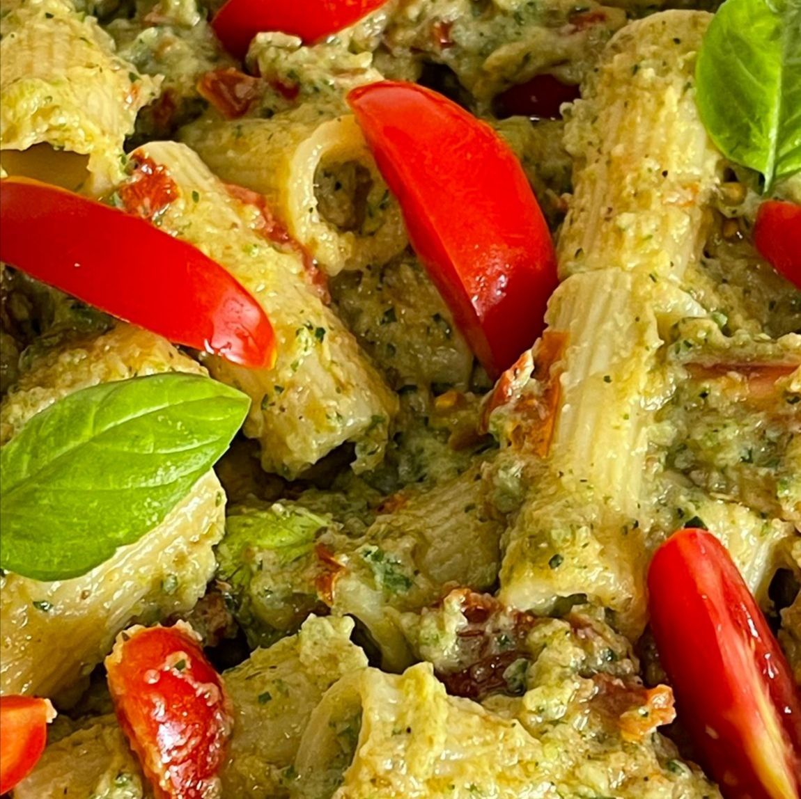 Un primo piano di un piatto di pasta con pomodori e basilico