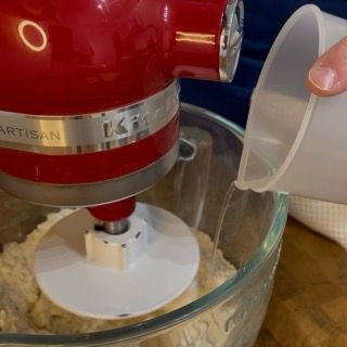 Una persona che versa del liquido in un mixer KitchenAid