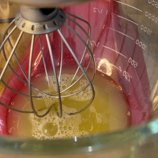 Primo piano di una frusta in un misurino pieno di liquido.