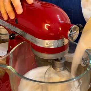 Una persona sta versando del liquido in un mixer KitchenAid