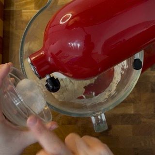 Una persona sta versando lo zucchero in un mixer rosso