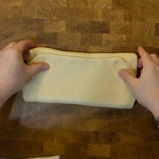 Una persona sta piegando un tovagliolo su un tavolo di legno.