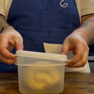 Un uomo con un grembiule blu sta aprendo un contenitore di plastica