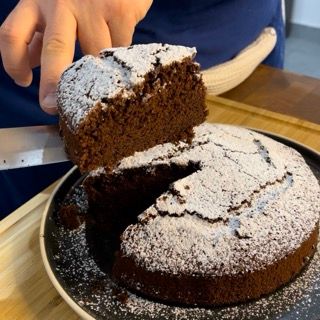 Una persona sta tagliando un pezzo di torta al cioccolato con zucchero a velo