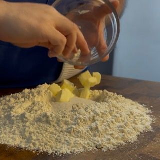 Ingredienti per la ricetta chiacchiere disposti a fontana con uova, zucchero e burro.