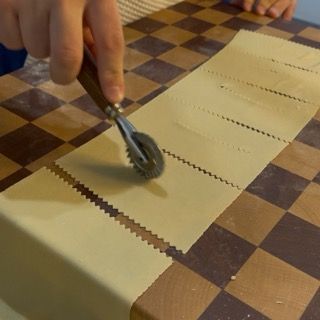 Taglio dei rettangoli di pasta con la rotella per la crostoli ricetta tradizionale.