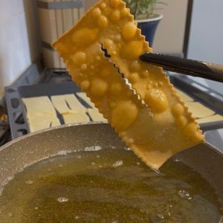 Scolatura delle chiacchiere su carta assorbente per eliminare l'olio in eccesso.