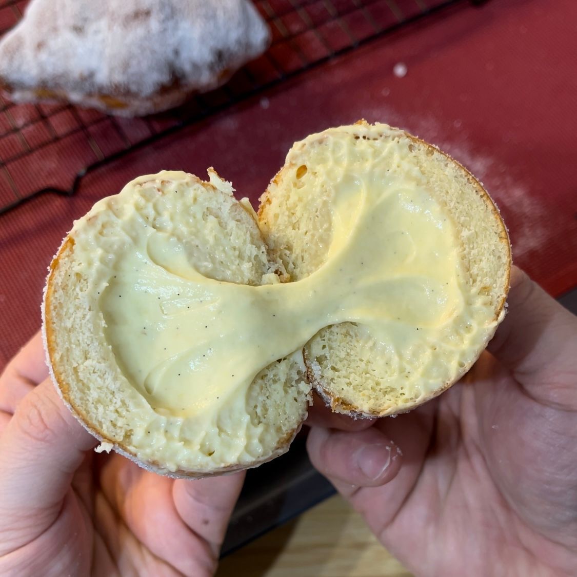 Una persona tiene in mano una ciambella mezza mangiata con del formaggio dentro