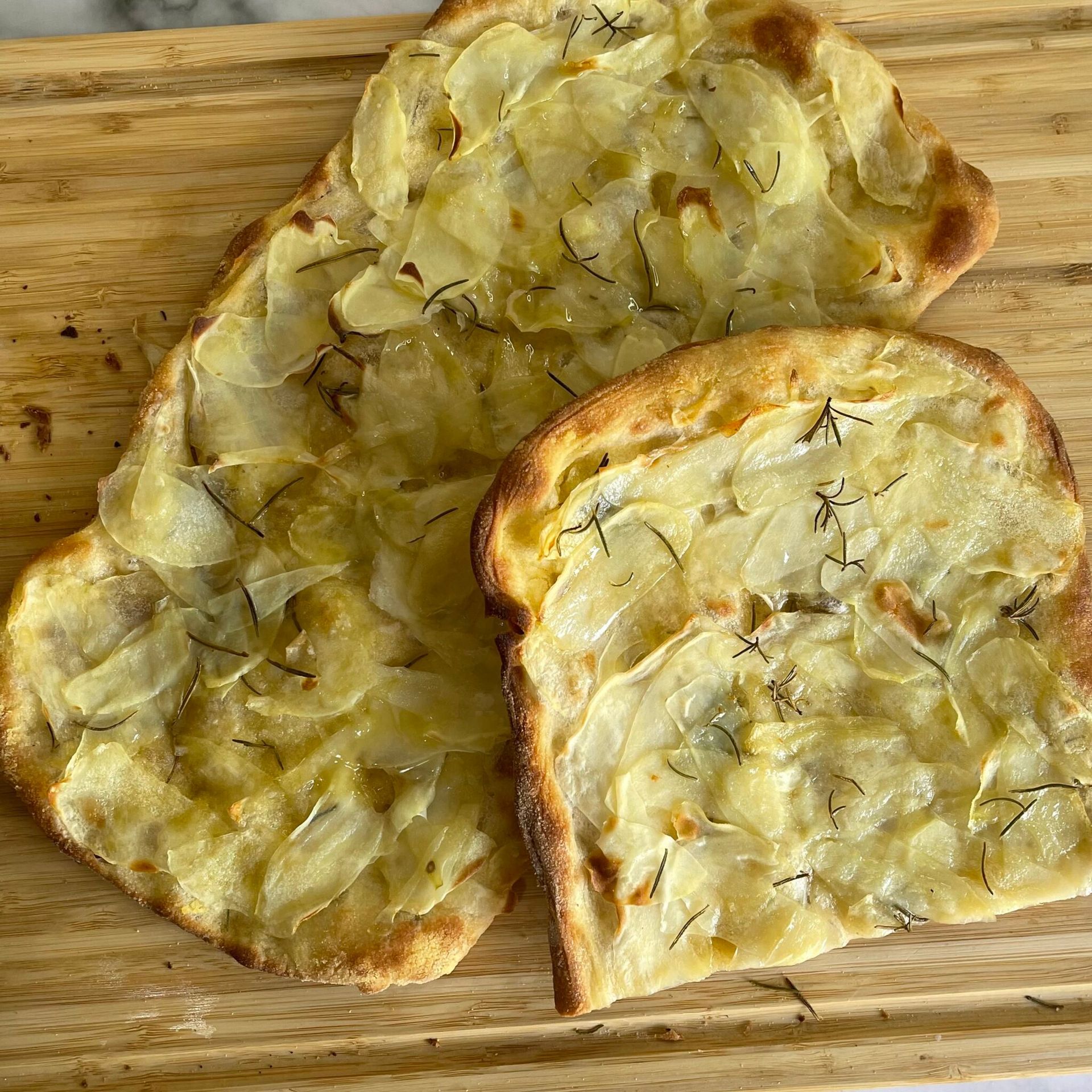 Due fette di pizza sono appoggiate su un tagliere di legno.