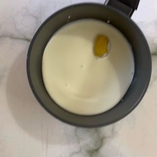 Una ciotola di latte con un uovo dentro su un tavolo.