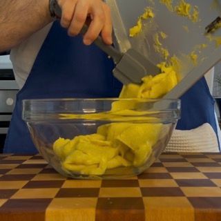 Una persona tiene una spatola sopra una ciotola di cibo