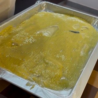 Un vassoio di cibo è avvolto nella plastica e appoggiato su un tavolo.