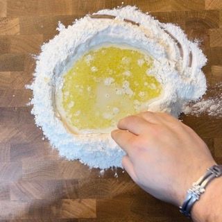 Una persona sta mescolando gli ingredienti in una ciotola di farina