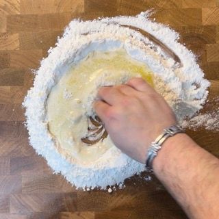 Una persona sta mescolando gli ingredienti in una ciotola di farina