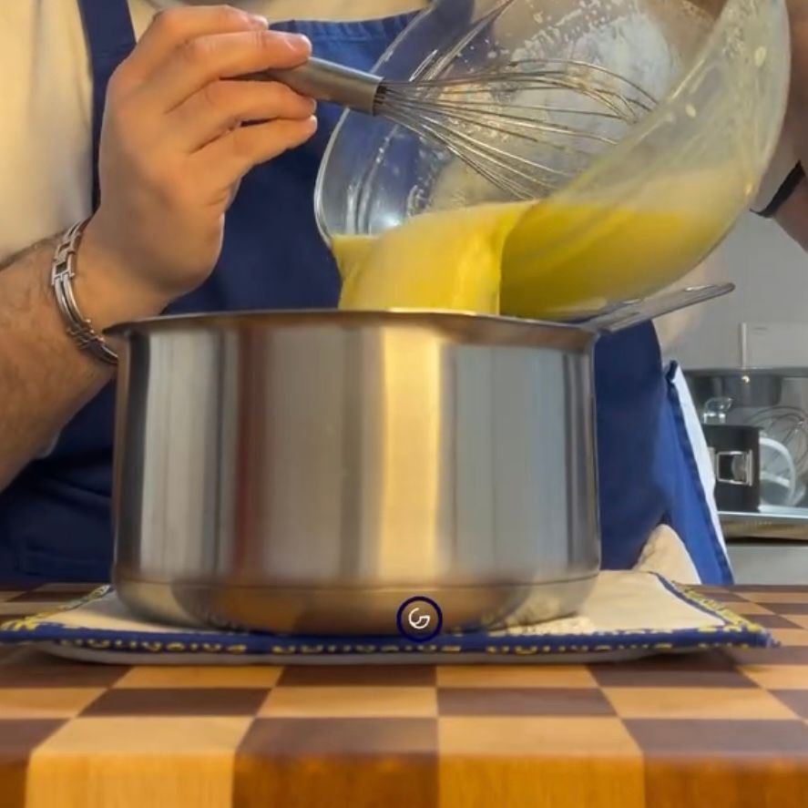 Crema base che cuoce nel pentolino a fuoco medio mescolata continuamente.